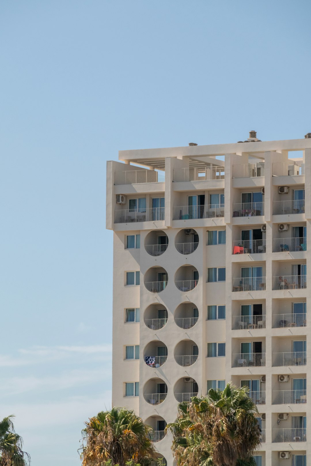 about-01 a-tall-white-building-with-balconies-on-the-top-of-it-nolcalpqcfw
